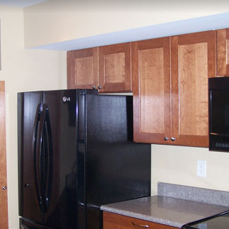 A kitchen with wooden cupboards and a black refrigerator